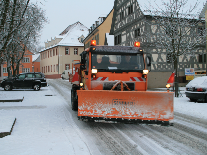 Schneepflug  fährt auf zugeschneiter Straße