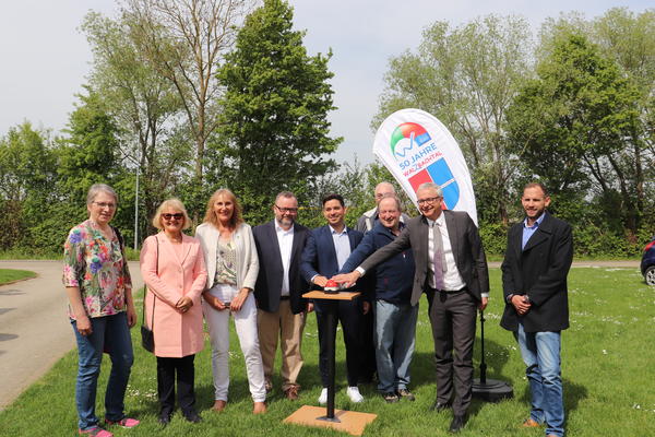 Eine Gruppe von neun Personen steht bei sonnigem Wetter auf einer Wiese vor einem Banner mit der Aufschrift "50 Jahre Walzbachtal". Einige drücken auf einen symbolischen Knopf, um den Start der Breitbandversorgung zu symbolisieren.