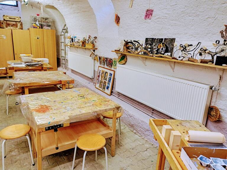 Kunstwerkstatt der Grundschule Wössingen, drei Werktische und viele Kunstwerke auf den Regalen