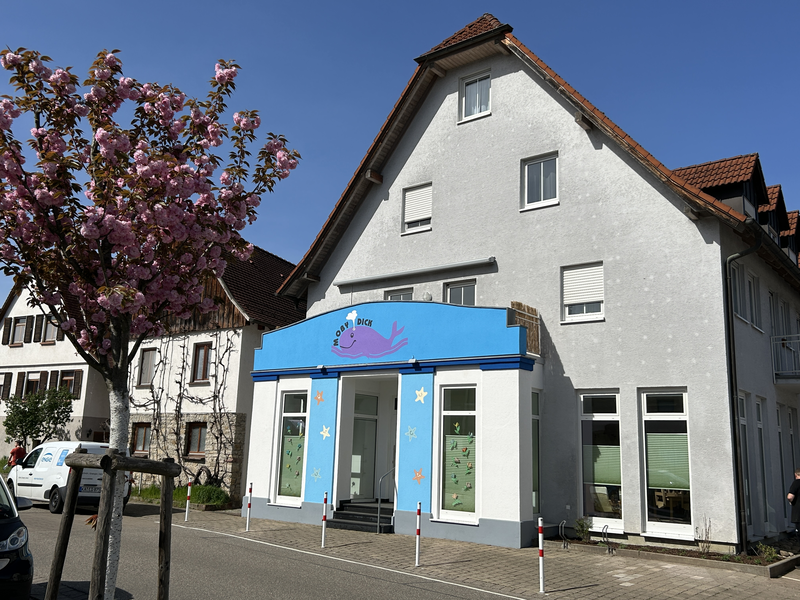 Außengruppe Seesterne. Weißes Gebäude. Vorder Gebäudeteil steht etwas hervor. Dieser ist hellblau mit einem abgebildeten Wal