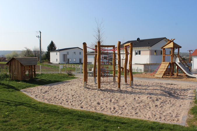 Spielplatz Bäderäcker mit drei verschiedenen Spielgeräten und Häusern im Hintergrund
