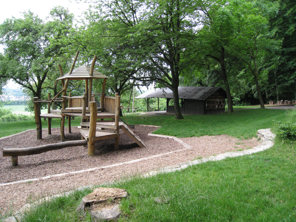 Spielplatz Fraueneiche, Spielgerät aus Holz, außenherum Wiese und eine Hütte