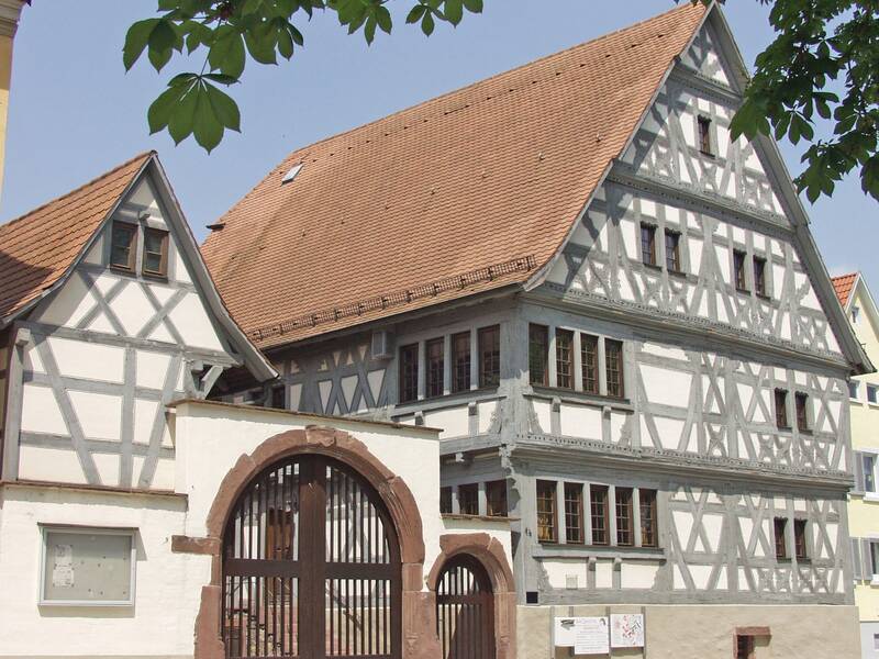 Speyerer Hof in Jöhlingen. Es handelt sich um ein Fachwerkhaus in grau weiß mit einem großen und einem kleine  Torbogen. Es gibt ein Hauptgebäude und ein Nebengebäude
