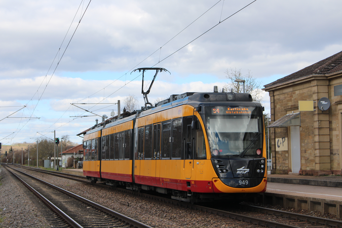 Straßenbahn S4 in gelb fährt auf dem Gleis. Daneben die Haltestelle