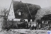 schwarz-weiß Bild einer Familie vor ihrem Wohnhaus mit Scheune