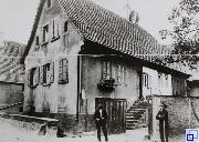 Schwarz-weiß Bild von zwei Personen vor einem Wohnhaus
